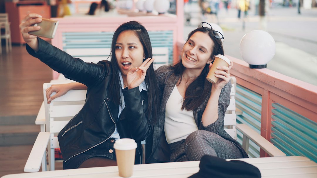 Mujeres utilizando un teléfono en una cafetería